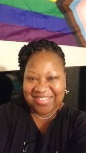 A smiling woman with a black shirt and braided hair.