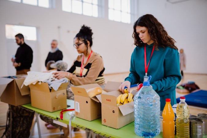 Volunteers sorting, packing clothes in cardboard boxes