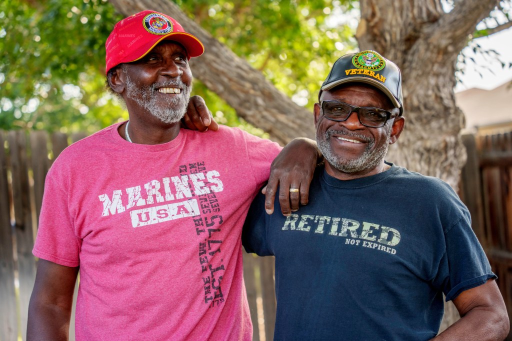 Two Senior African American Military Veterans Embracing Outside in a Backyard Having a Friendly Conversation